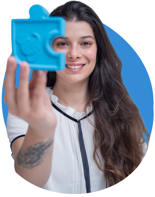 Juliana Meotti sorrindo, segurando diante do rosto uma peça de quebra-cabeça azul.